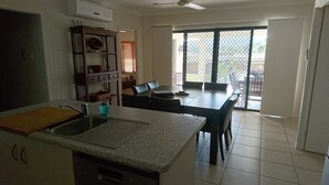 A kitchen with granite countertops, a built-in oven, and a dining area with a table and chairs. - Palm Lakeside - Bowen, Whitsundays Wifi Netflix Private Cool Luxury (Bowen)