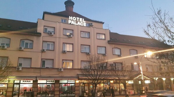 A hotel building with multiple windows and a sign that reads "HOTEL PALACE".
