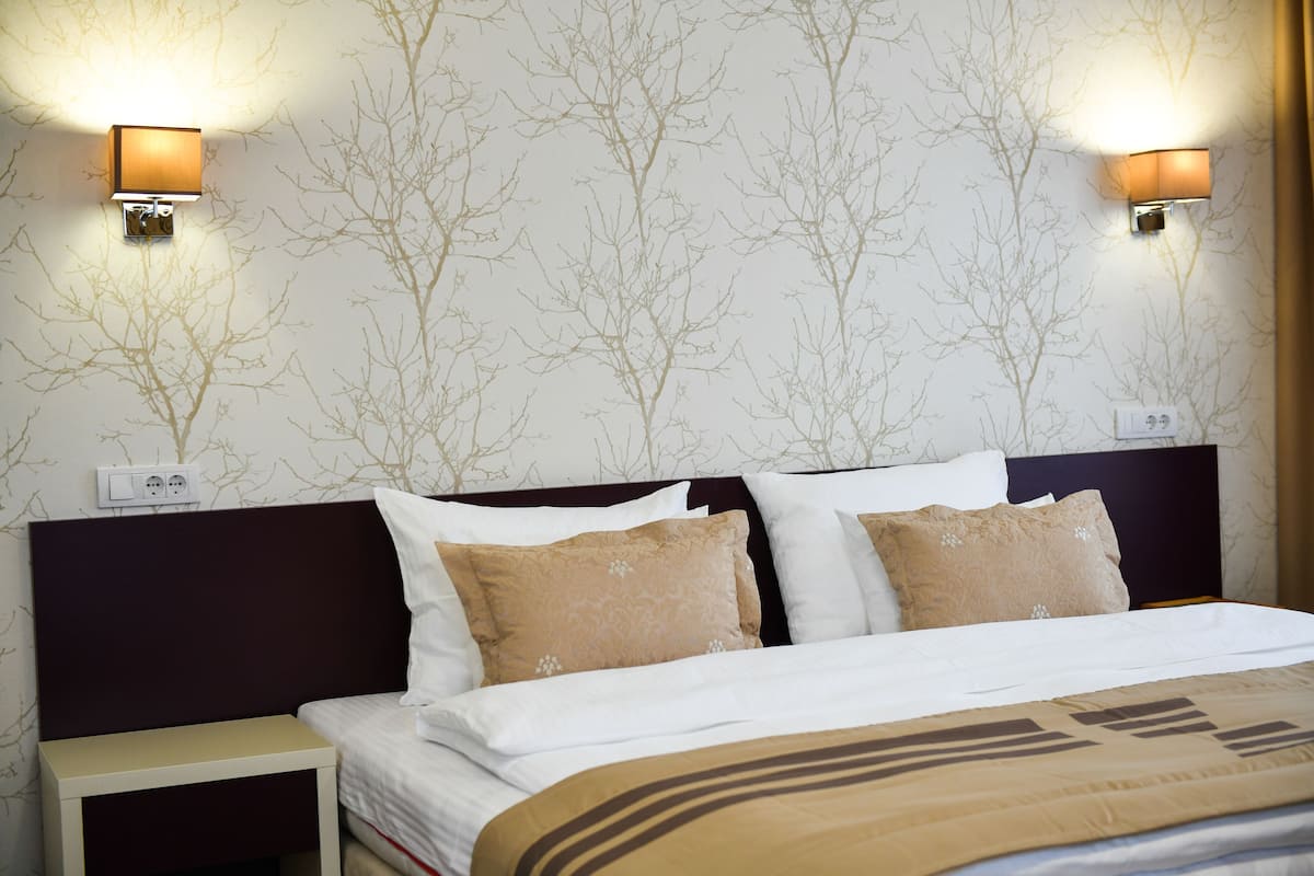 A hotel room with a bed, nightstands, and wall-mounted lamps.