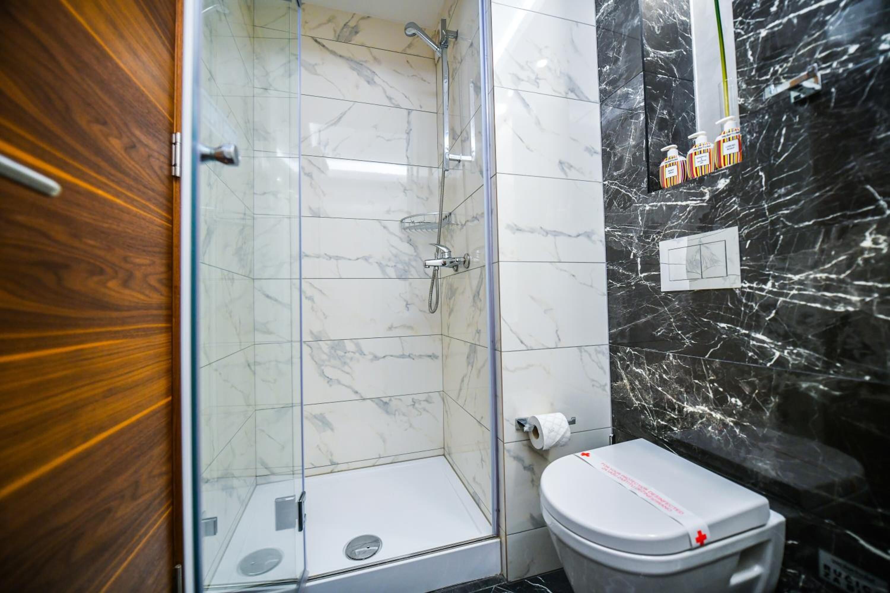 A bathroom with a shower, toilet, and marble walls.