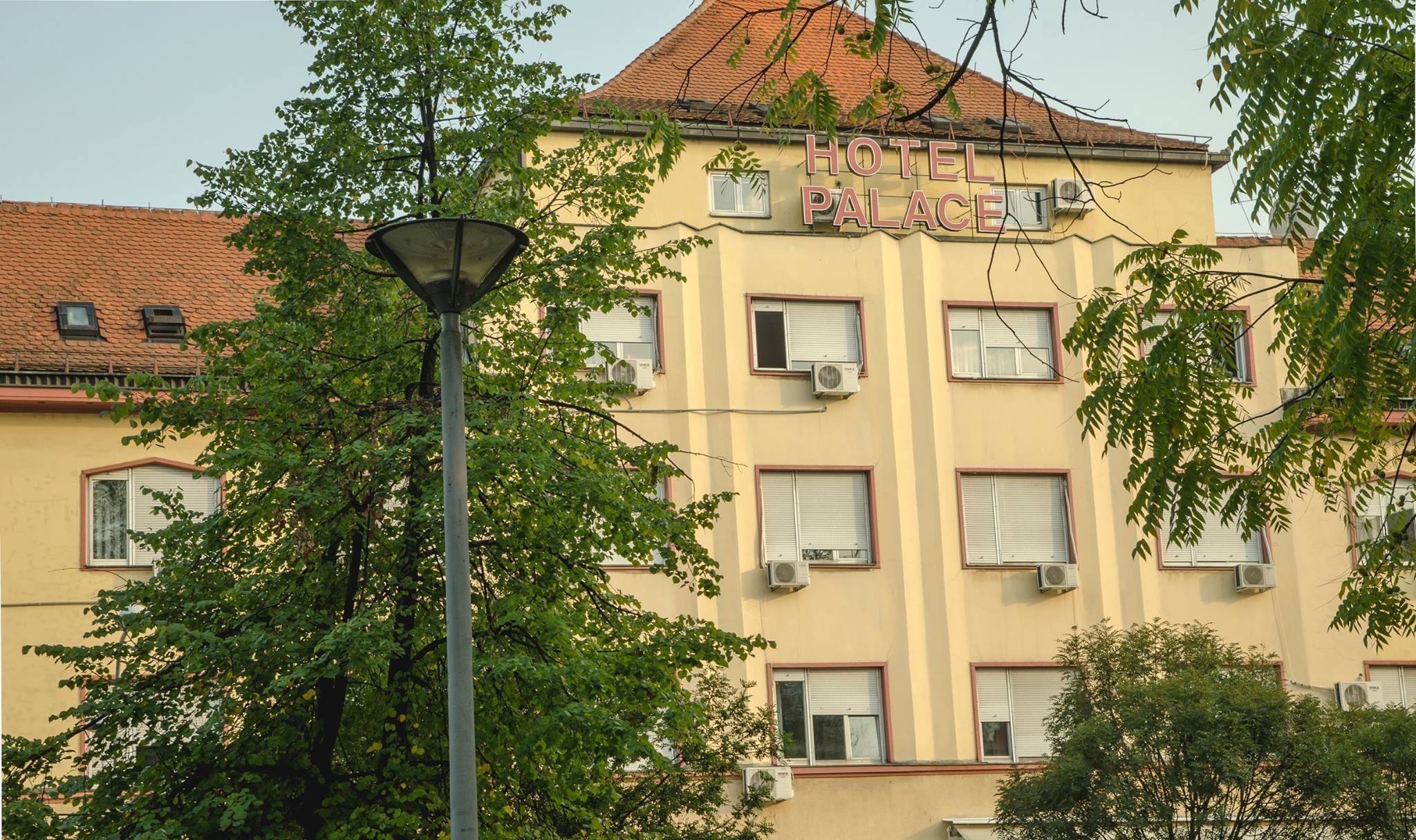Un immeuble sur lequel on peut lire l’inscription « HÔTEL PALACE » et qui possède de nombreuses fenêtres équipées de climatiseurs.