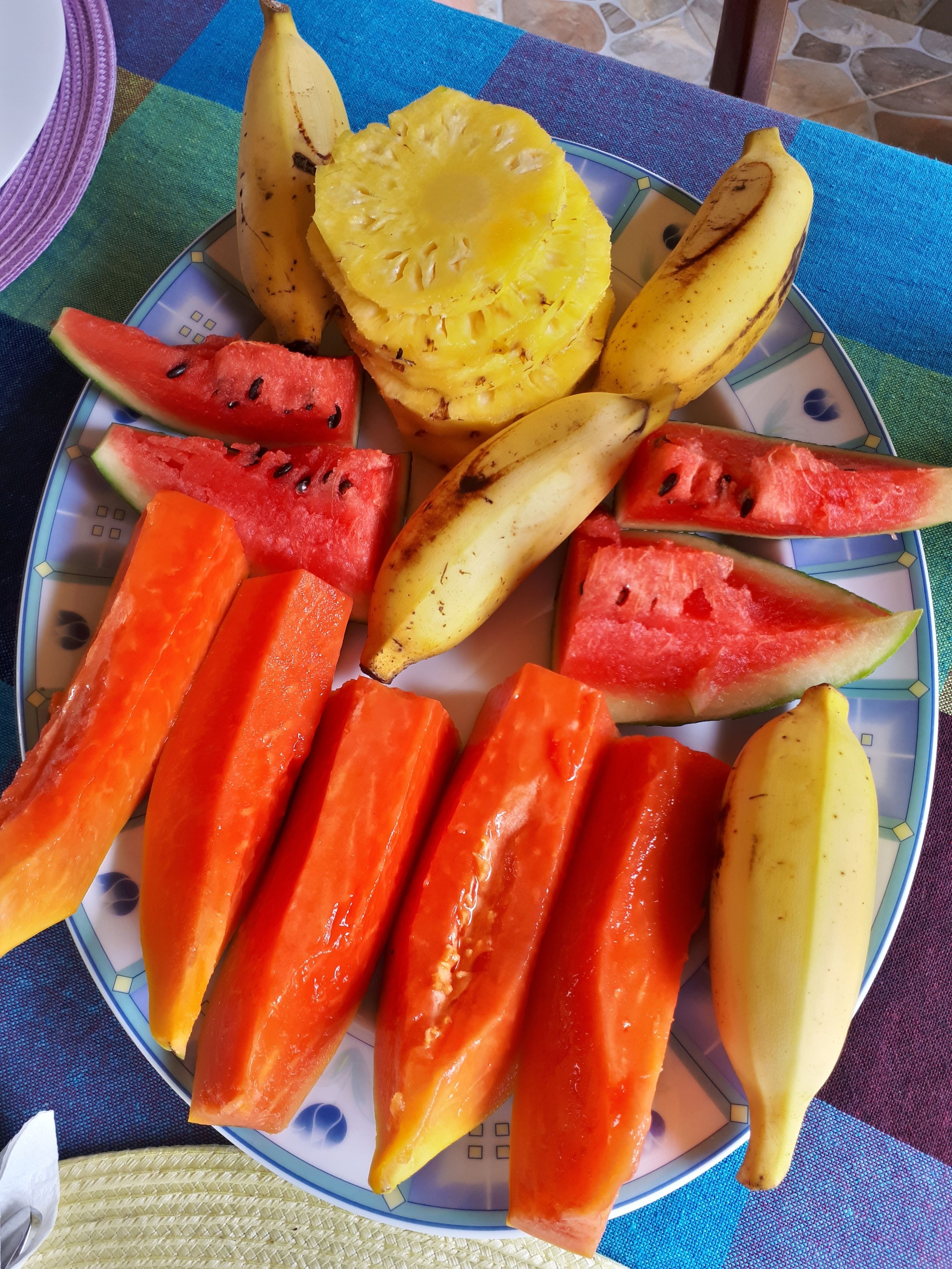 Un plato con frutas cortadas, como sandía, piña, plátano y papaya.