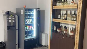 A room with a vending machine, a refrigerator, and a liquor cabinet.