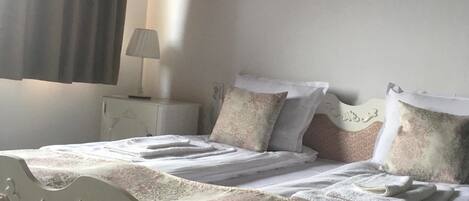 A neatly made bed with a patterned bedspread, a bedside table with a lamp, and a wall-mounted picture.