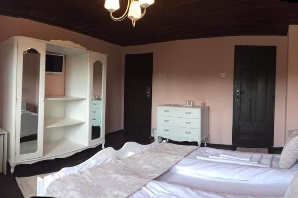 Een slaapkamer met een bed, een garderobe, een dressoir en een nachtkastje.
