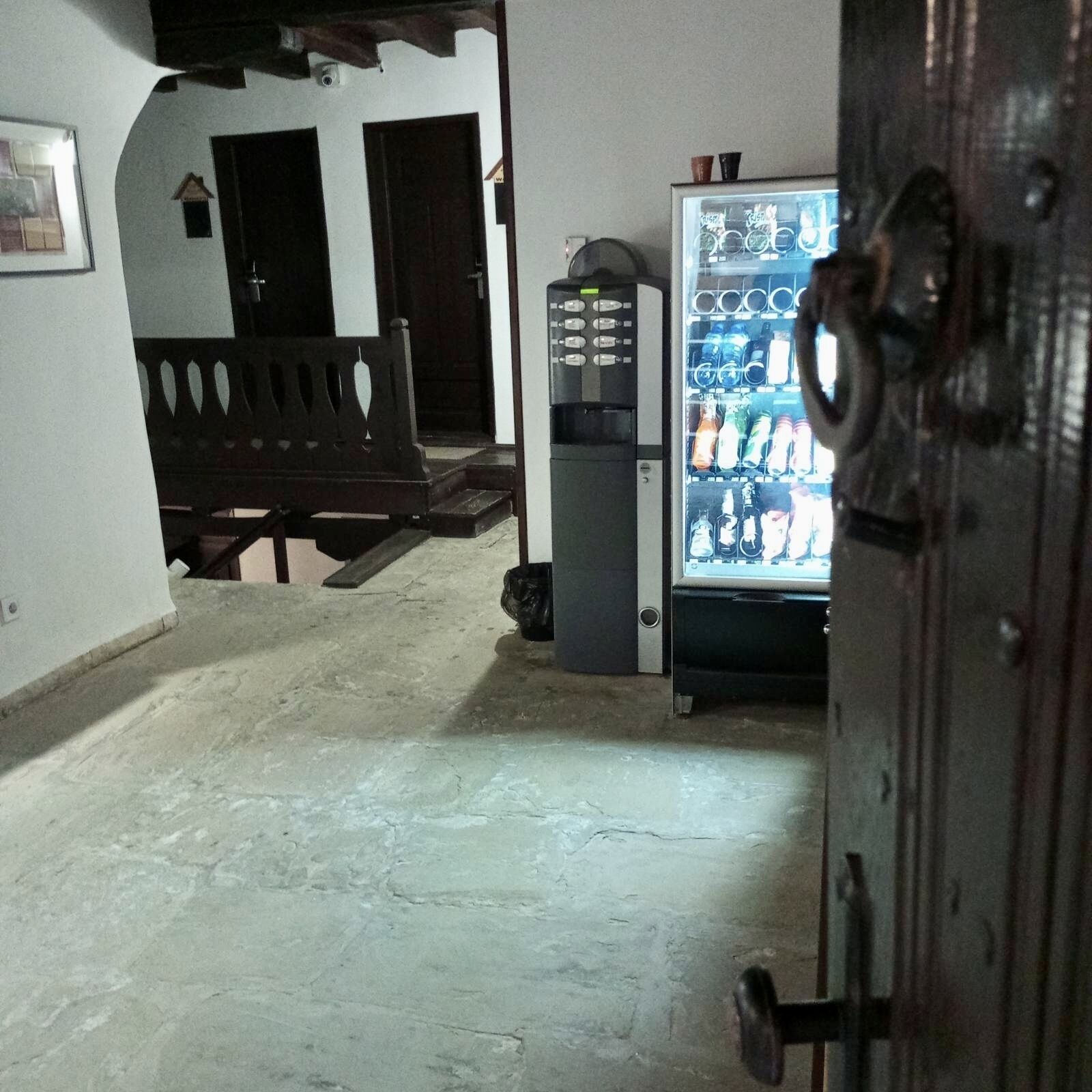 Un pasillo con una máquina expendedora, un banco y una puerta.