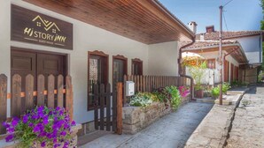 A guesthouse with a wooden facade, a sign reading "Hi Story Inn," and a stone pathway leading to the entrance.