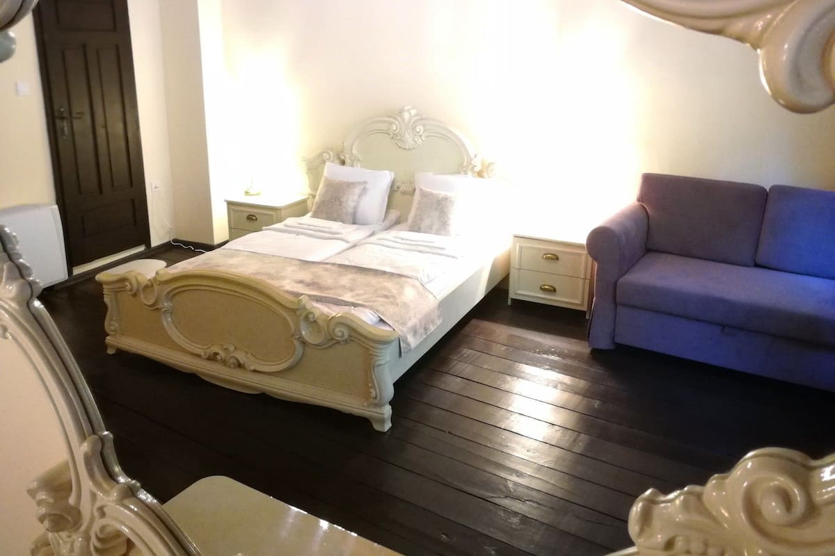 Een slaapkamer met een bed, nachtkastjes, een dressoir en een slaapbank.