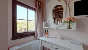 A room with a window, a white dresser, a mirror, and a television.