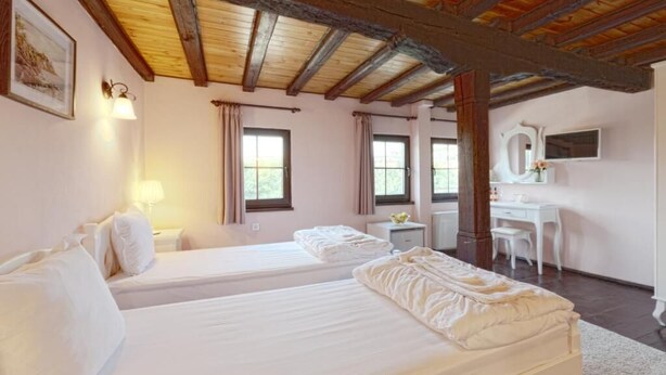 A room with two beds, a desk, a chair, and a mirror.