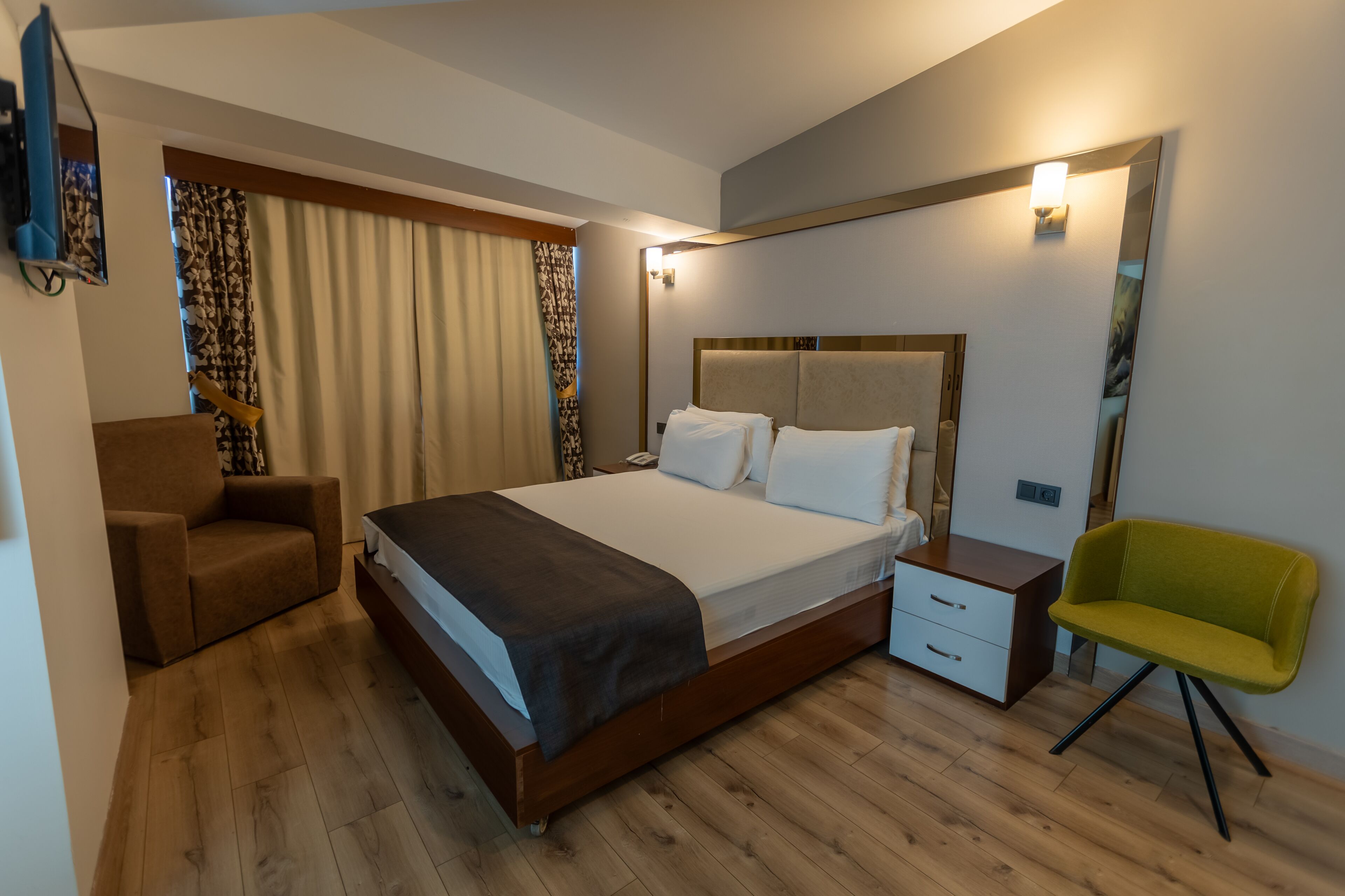 A hotel room with a bed, a nightstand, a chair, a dresser, and a mirror.