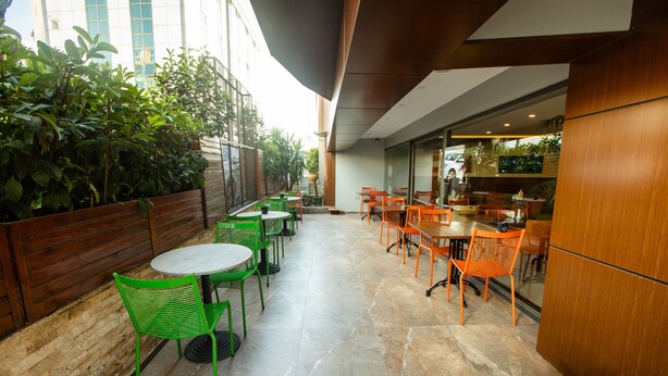 An outdoor patio area with green and orange chairs, a wooden fence, and a view of the street. - Asia Business Suites (Istanbul)