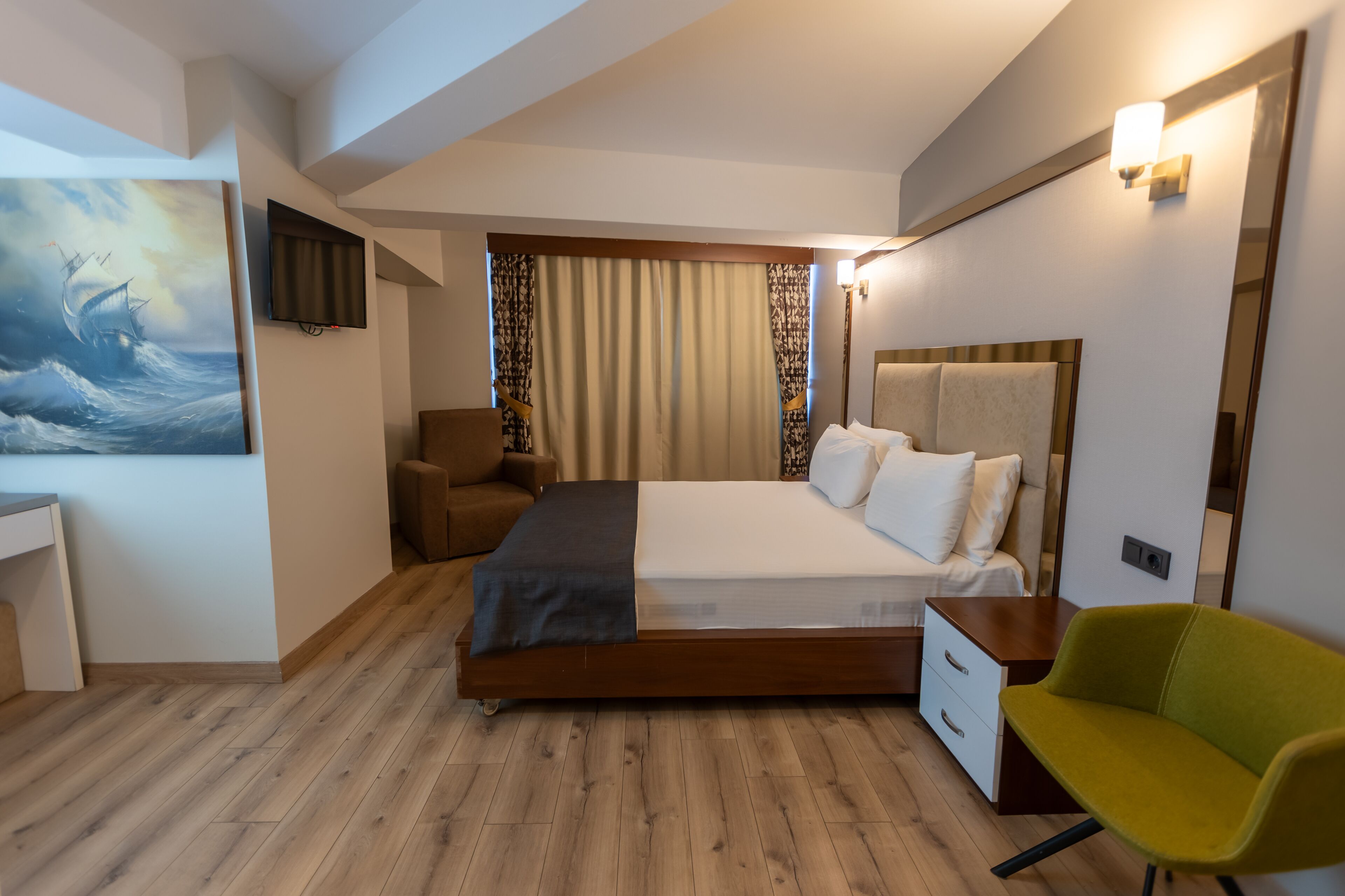 Une chambre d’hôtel moderne, équipée d’un lit, d’un bureau, d’une chaise et d’un tableau au mur.