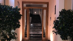 Een trap die naar de tweede verdieping leidt, met aan weerszijden twee potplanten.