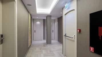 Un pasillo moderno de hotel con suelo de diseño geométrico, iluminación empotrada en el techo y puertas numeradas 116 y 110.