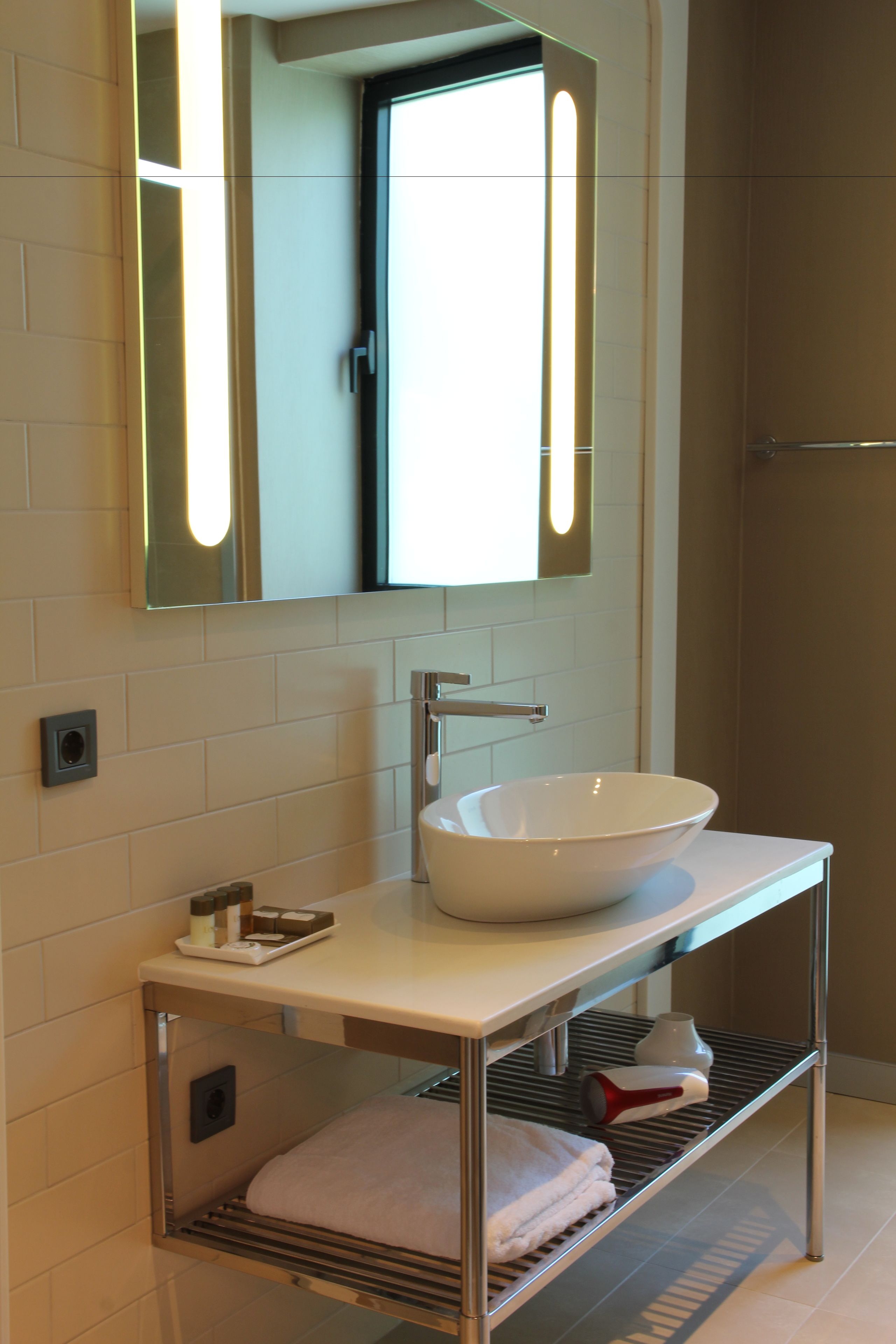 A modern bathroom with a white sink, a mirror, and a towel rack.