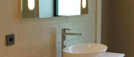 A modern bathroom with a white sink, a mirror, and a towel rack.
