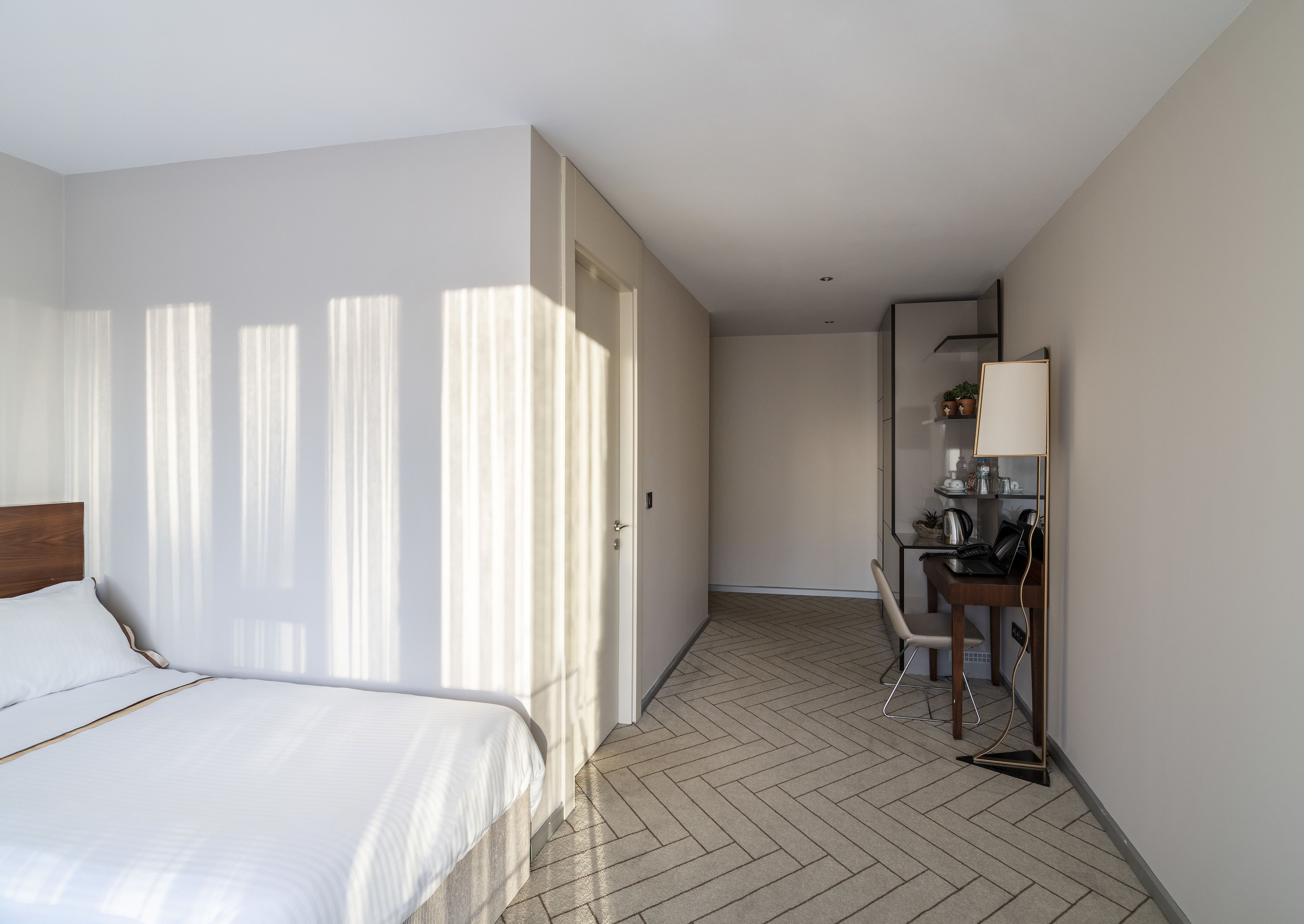 A hotel room with a bed, a desk, and a chair.