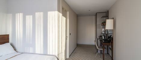 A hotel room with a bed, a desk, and a chair.