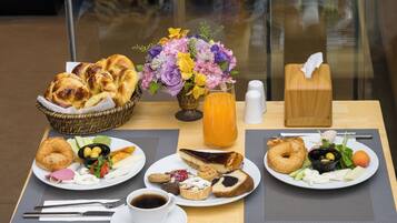 Un bufé de desayuno con diversos pasteles, frutas y bebidas sobre una mesa.