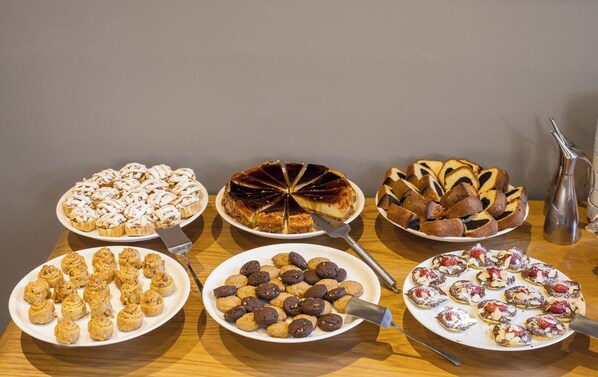 Variedad de postres en platos, incluyendo tartas, galletas y pasteles, dispuestos sobre una mesa de madera.