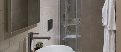 A modern bathroom with a large mirror, a white sink, and a glass shower enclosure.