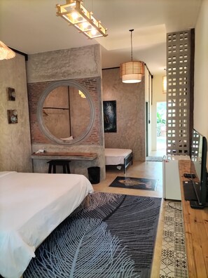 Quarto com uma cama grande, uma janela redonda, uma escrivaninha e uma televisão.