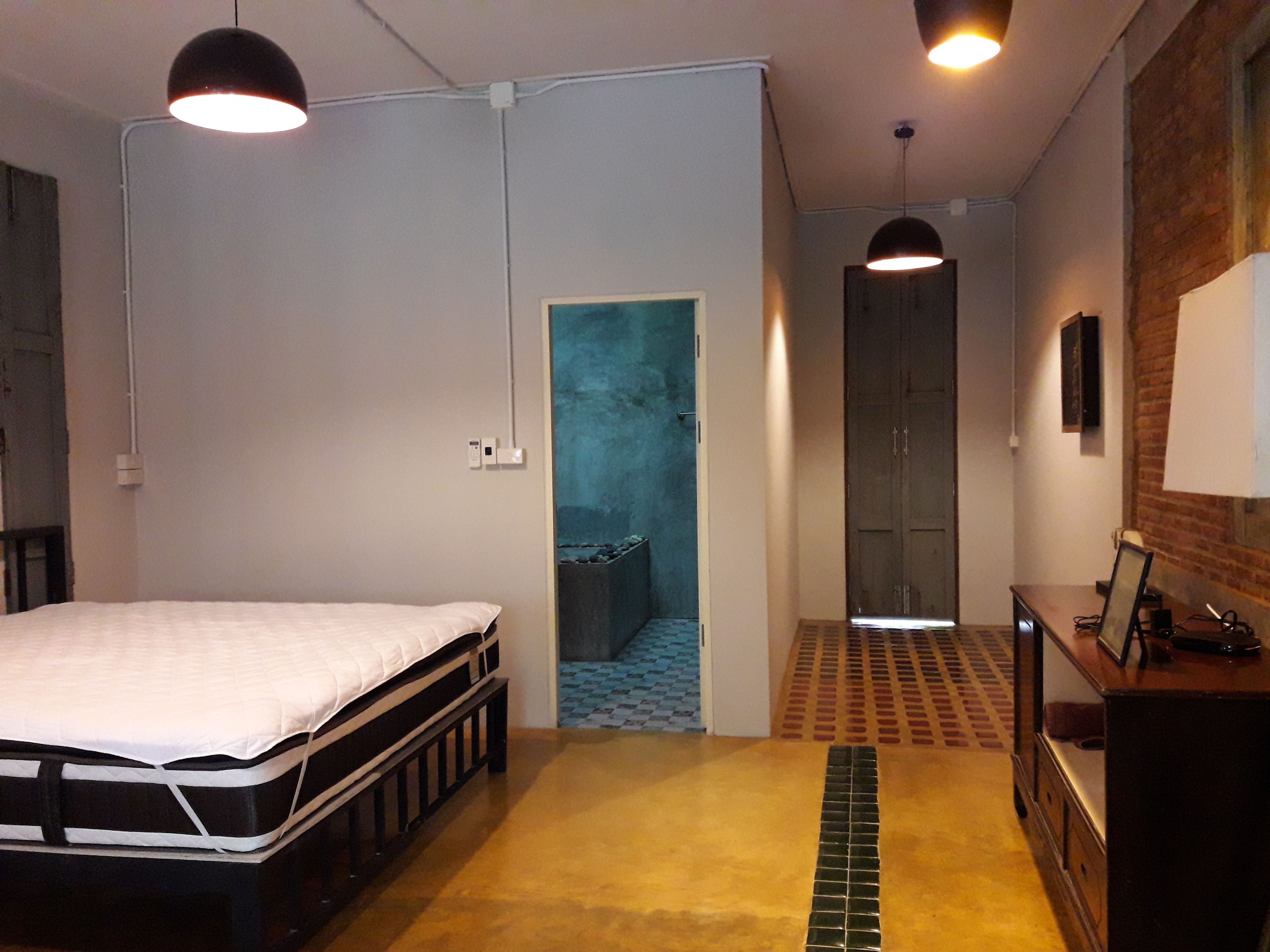A bedroom with a bed, a desk, and a wardrobe. There is a door leading to a bathroom.