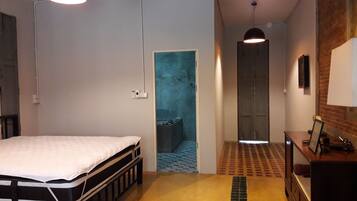 A bedroom with a bed, a desk, and a wardrobe. There is a door leading to a bathroom.