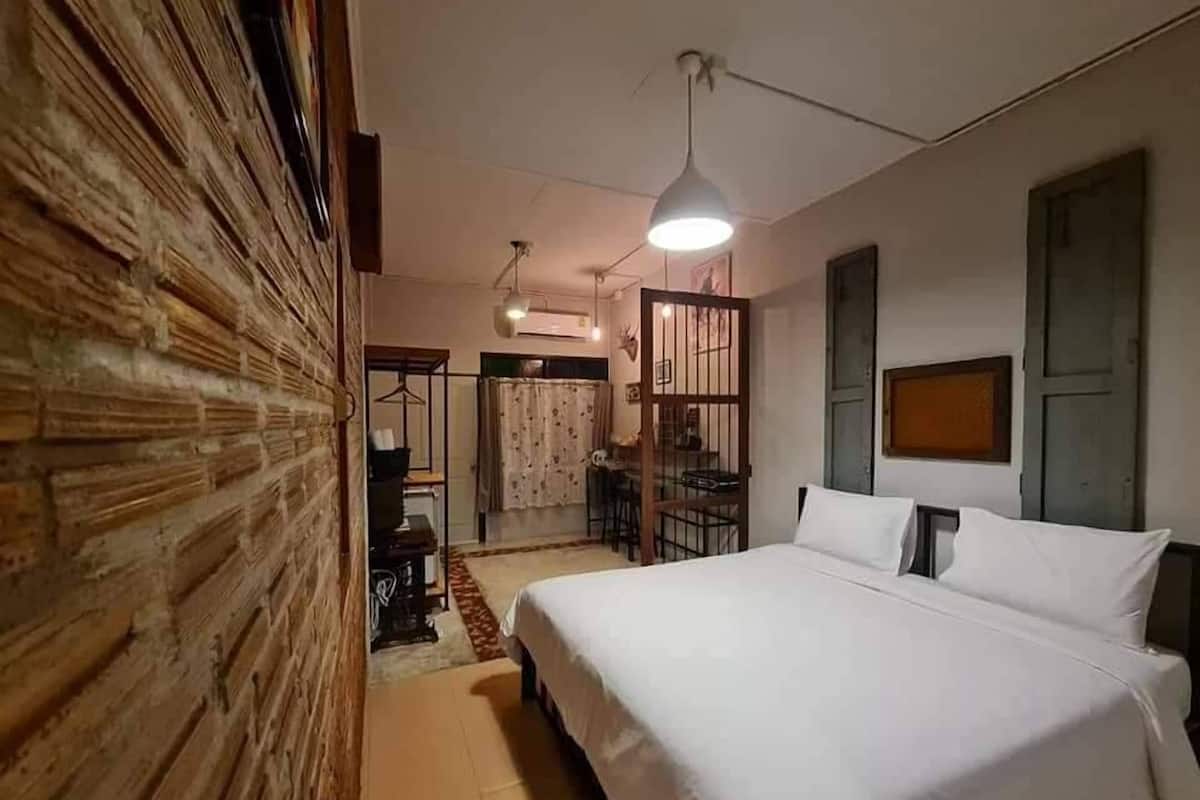 Quarto com uma cama grande, parede de madeira, ventilador de teto e luminária pendente.