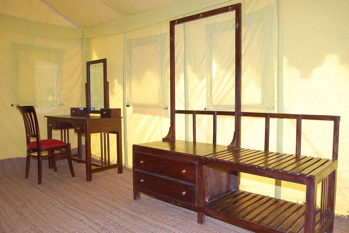 A bedroom with a wooden bed, a desk, a chair, and a mirror.