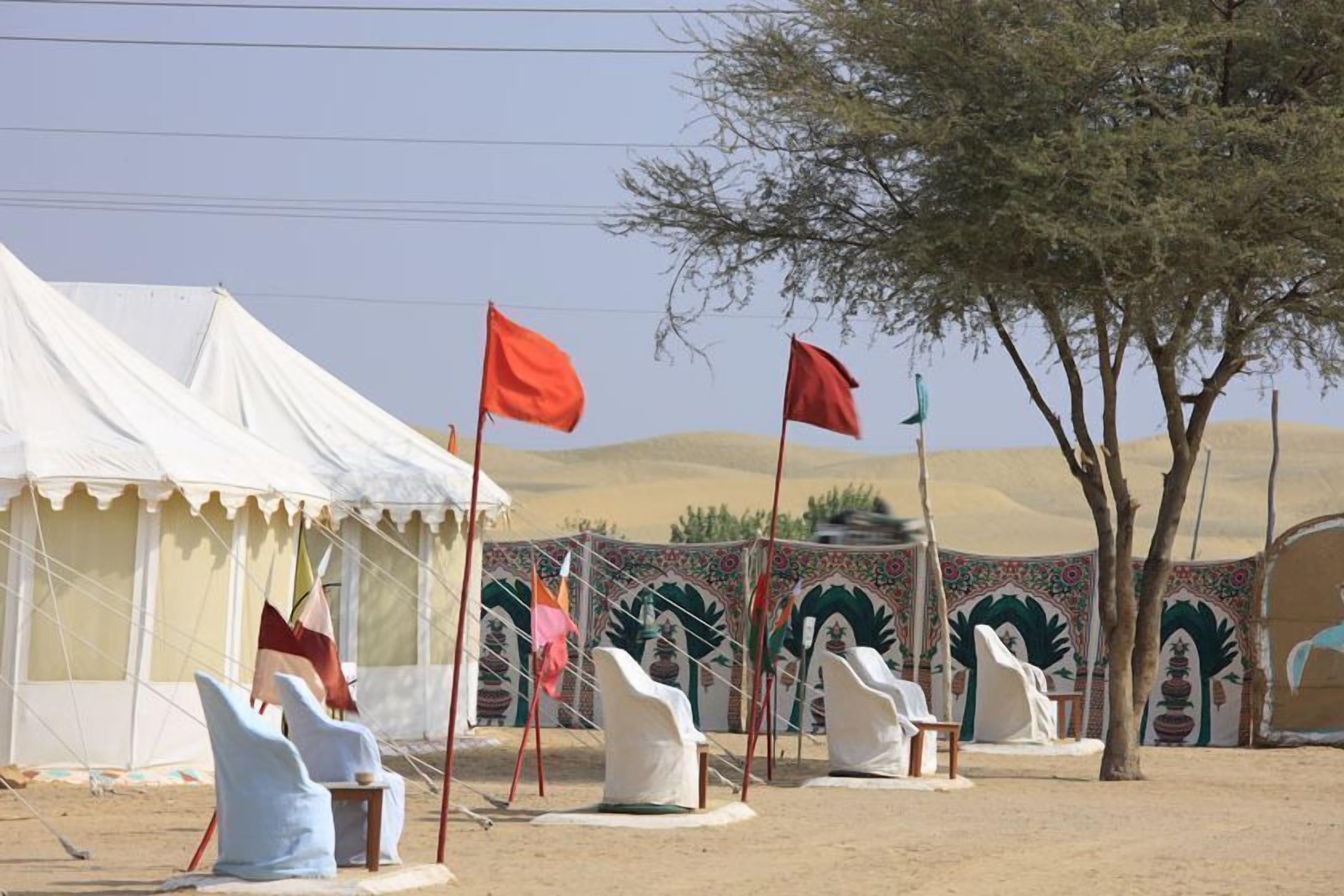 A desert setting with tents and covered seating areas, suggesting a temporary accommodation setup.