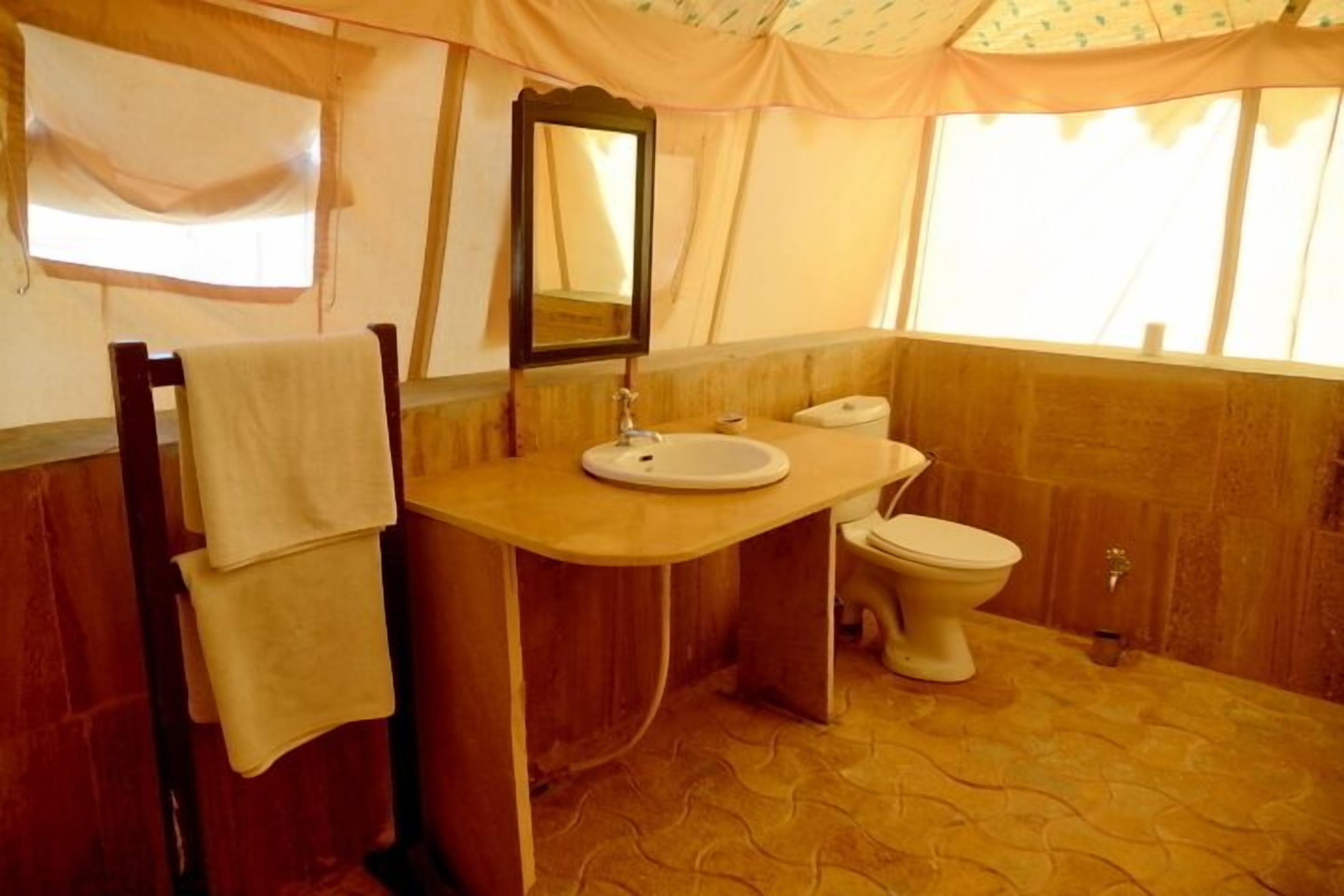 Une salle de bain avec un meuble-lavabo en bois, un évier, des toilettes et un miroir.