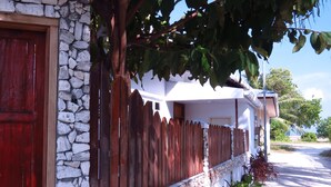 Uma casa com parede de pedra, porta de madeira e cerca de madeira.