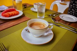 A table with a cup of coffee, a glass of water, and a plate of sliced fruit. - The Sunrise Huraa (Huraa)