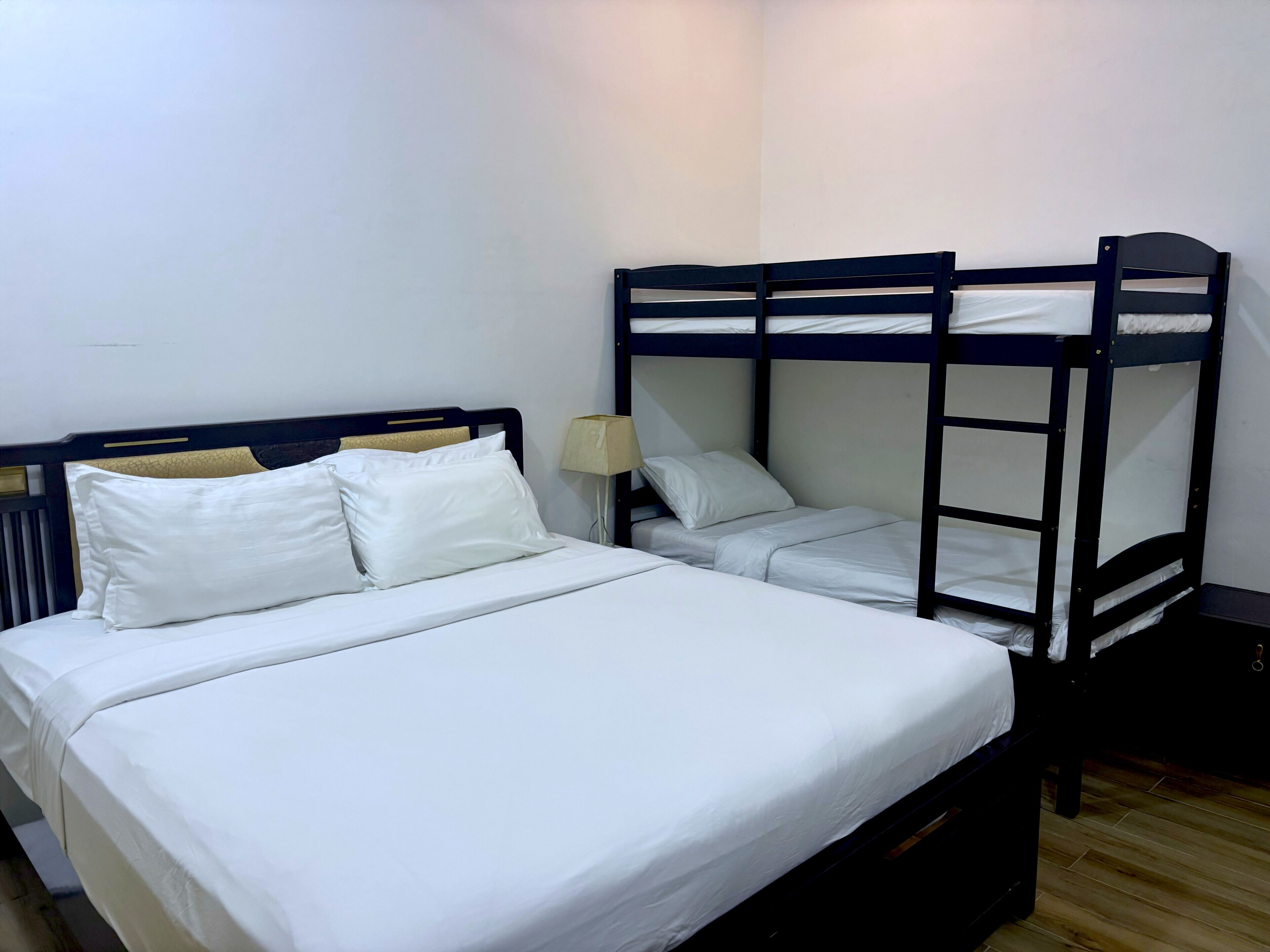 A room with a bunk bed and a single bed, both with white bedding.