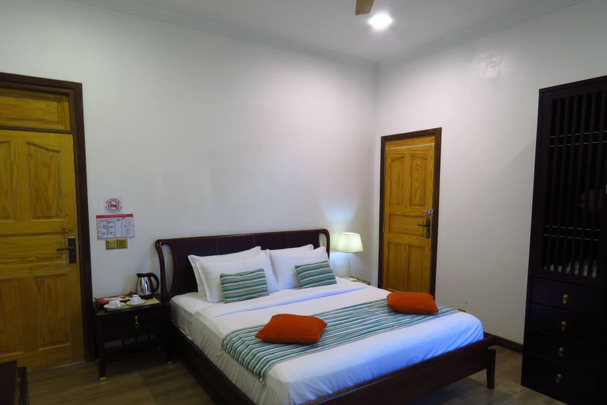 A neatly arranged bedroom with a wooden bed, a nightstand, a lamp, and a wardrobe.
