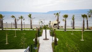 A pathway leading to a beach with palm trees and a view of the sea. - Sunsan Hotel (Çanakkale)