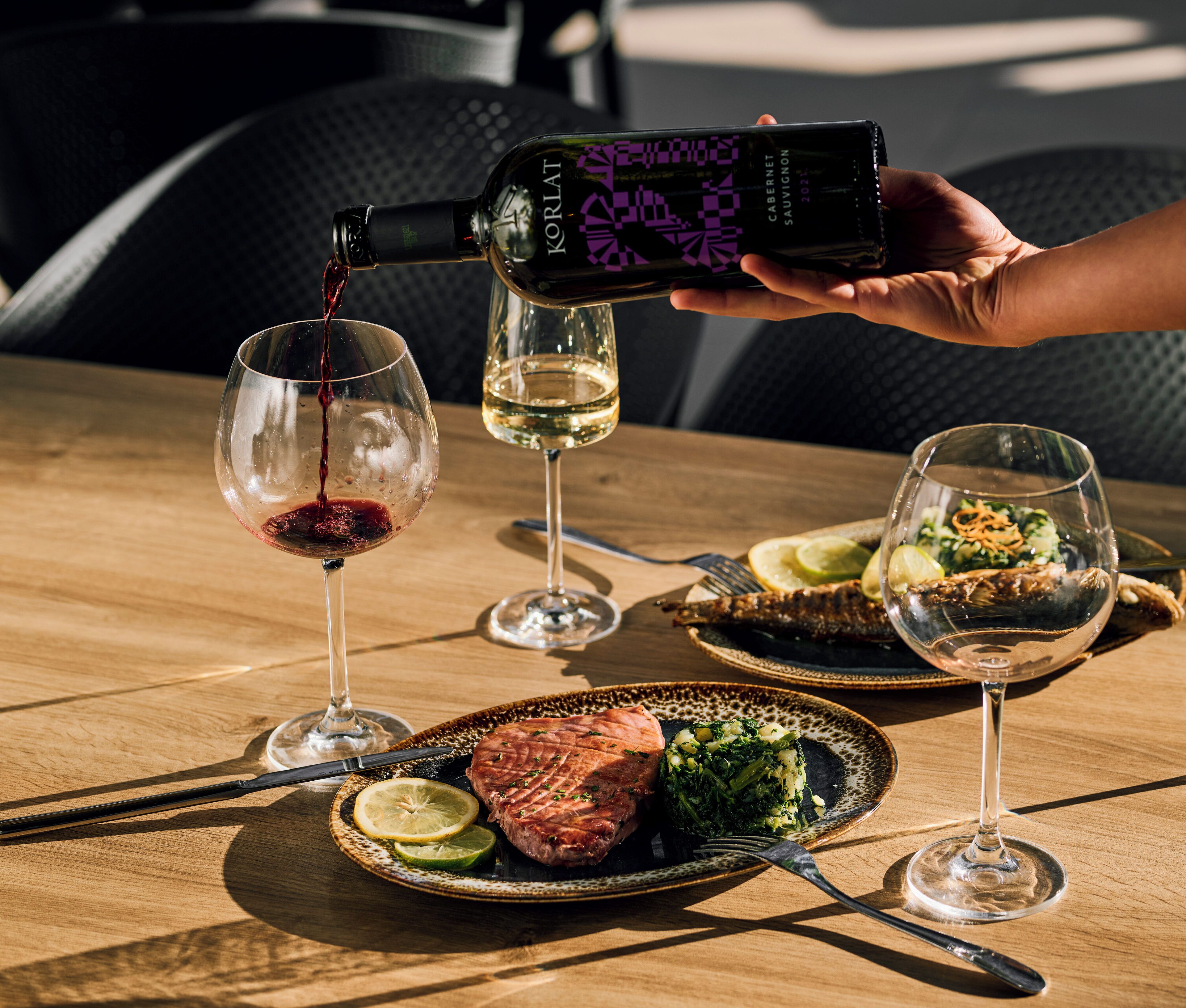 A bottle of Korlat Cabernet Sauvignon being poured into a glass.