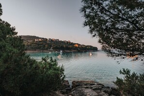 Un paisaje costero con vista despejada al mar, una costa rocosa y edificios en una colina al fondo.