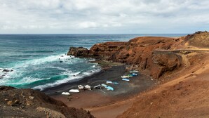 A coastal landscape with rocky terrain and a beach. - El Hotelito Del Golfo (Yaiza)