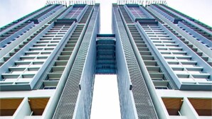 Een modern hoog gebouw met een symmetrische gevel, met een centraal atrium met glazen balustrades en een zichtbare ingang naar een boetiekhotel genaamd 'Atlantis Residences'.