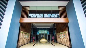 Een moderne hotellobby met een centraal atrium, houten lambrisering en een bord met de tekst 'Atlantis Residence'.