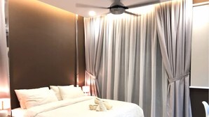 Een hotelkamer met een bed, gordijnen, een plafondventilator en een nachtkastje met een lamp.