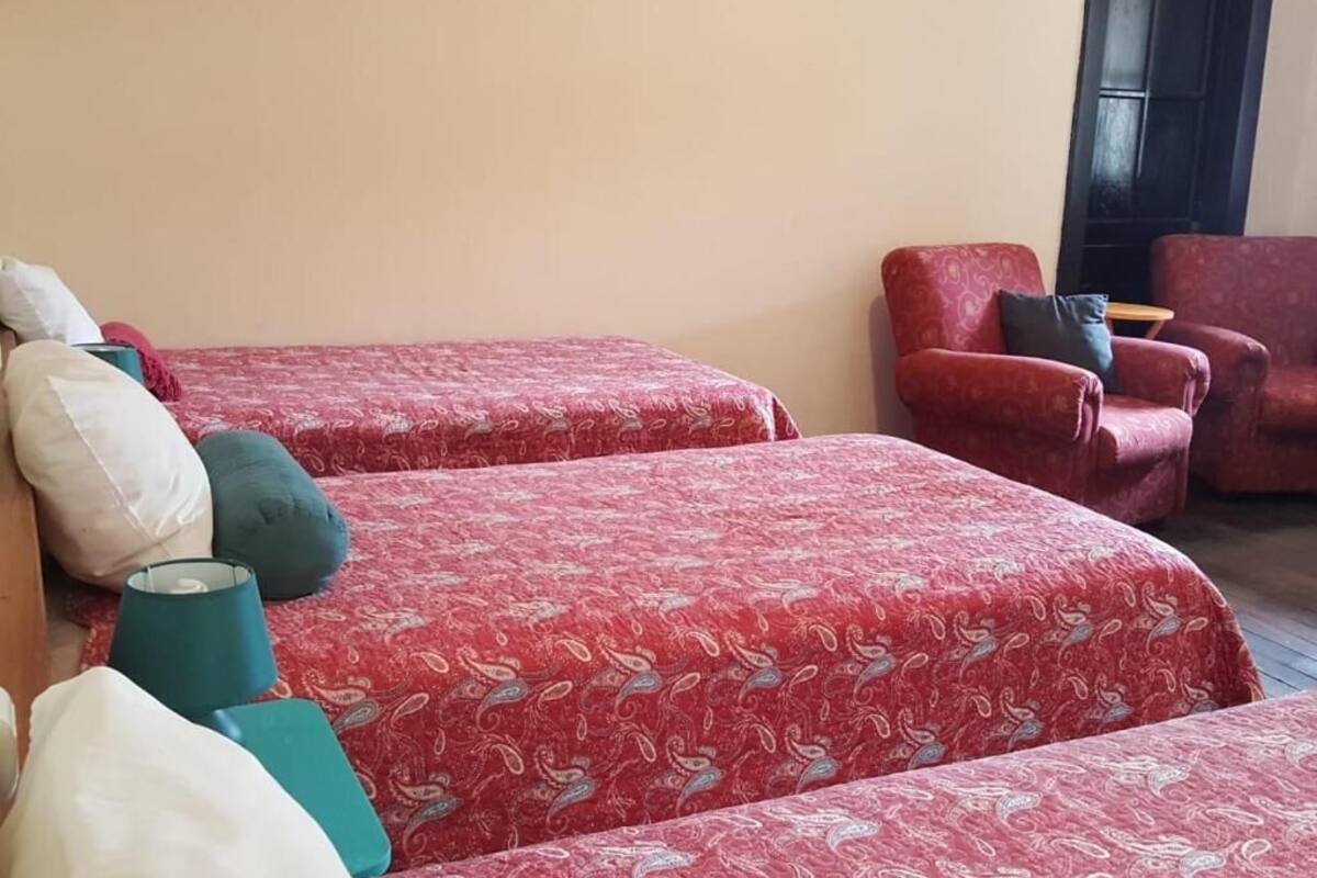 A room with two beds, a red armchair, and a small table.