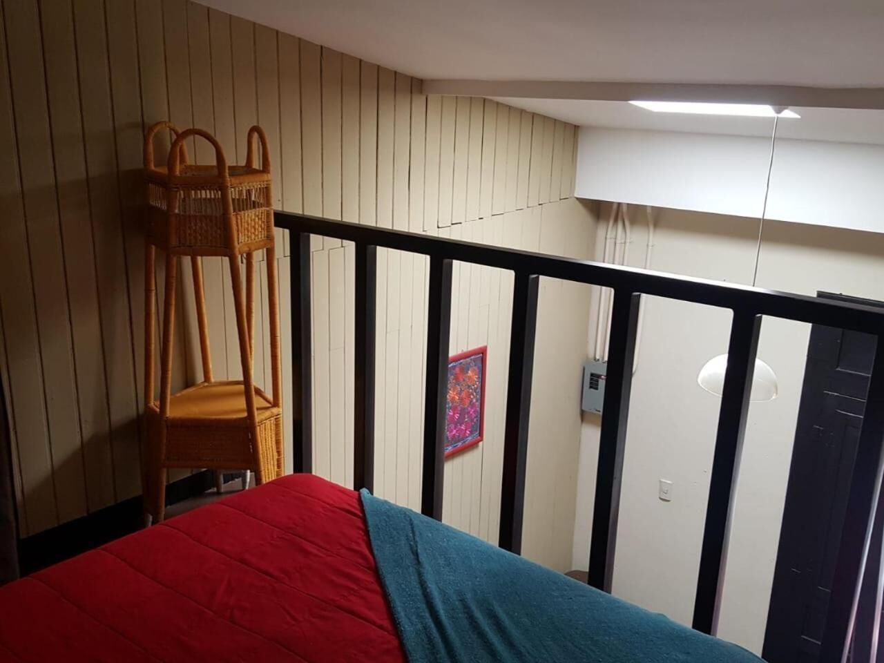 A room with a bed, a wooden chair, a door, and a wall with vertical lines.
