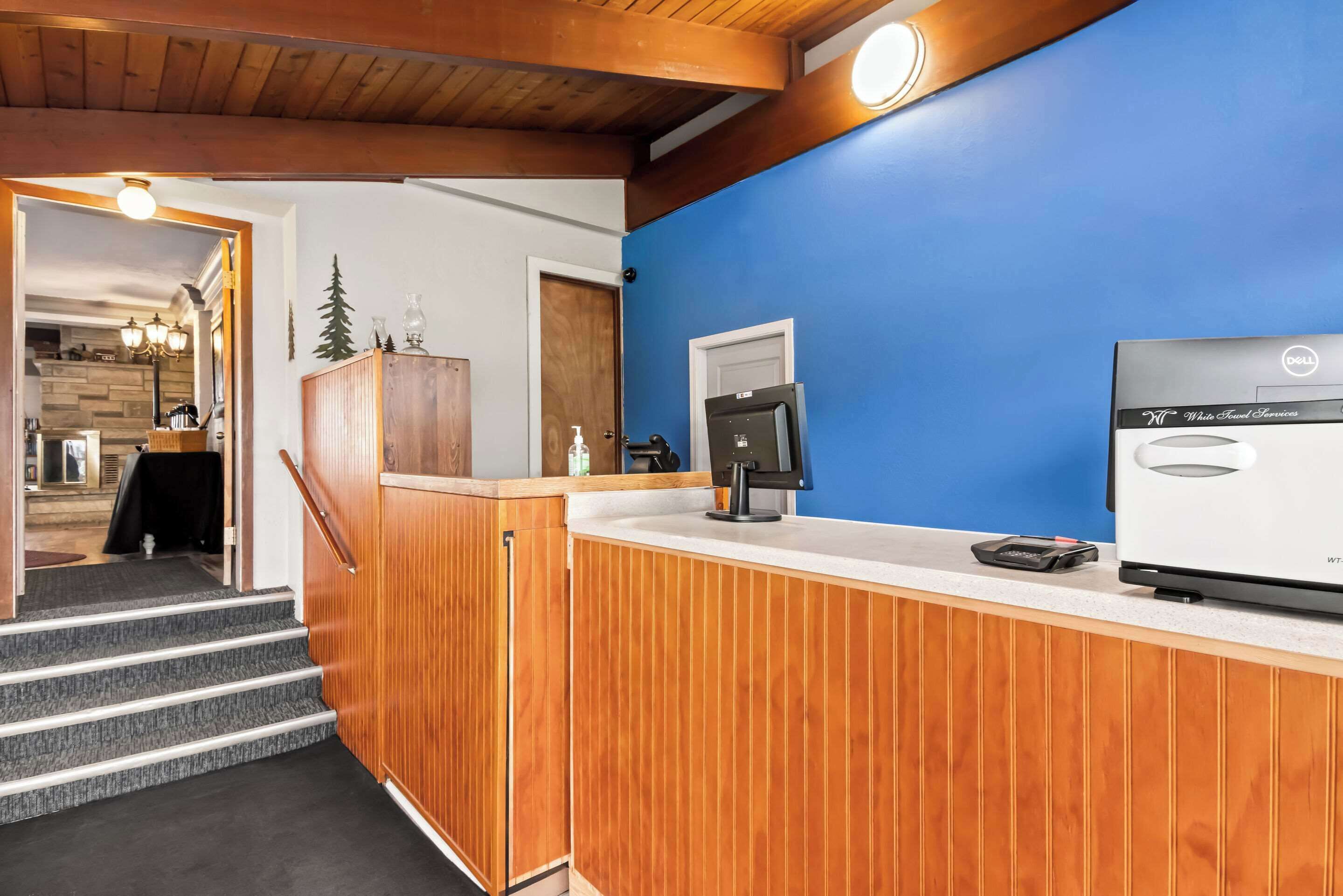 Un área de recepción con mostrador de madera, refrigerador blanco y pared azul.