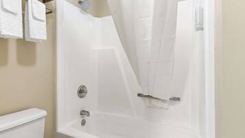 A white bathtub with a shower curtain, a towel rack with white towels, and a toilet.