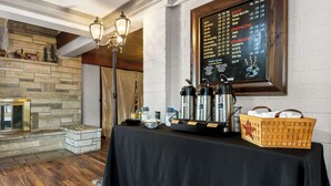 A hotel room with a stone fireplace, a black table with coffee-making equipment, and a menu on the wall. - Rodeway Inn Oscoda (Oscoda)