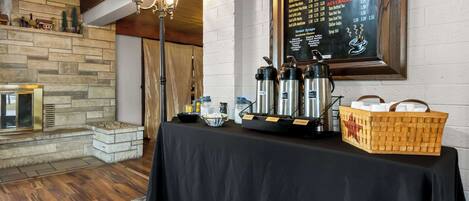 A hotel room with a stone fireplace, a black table with coffee-making equipment, and a menu on the wall.